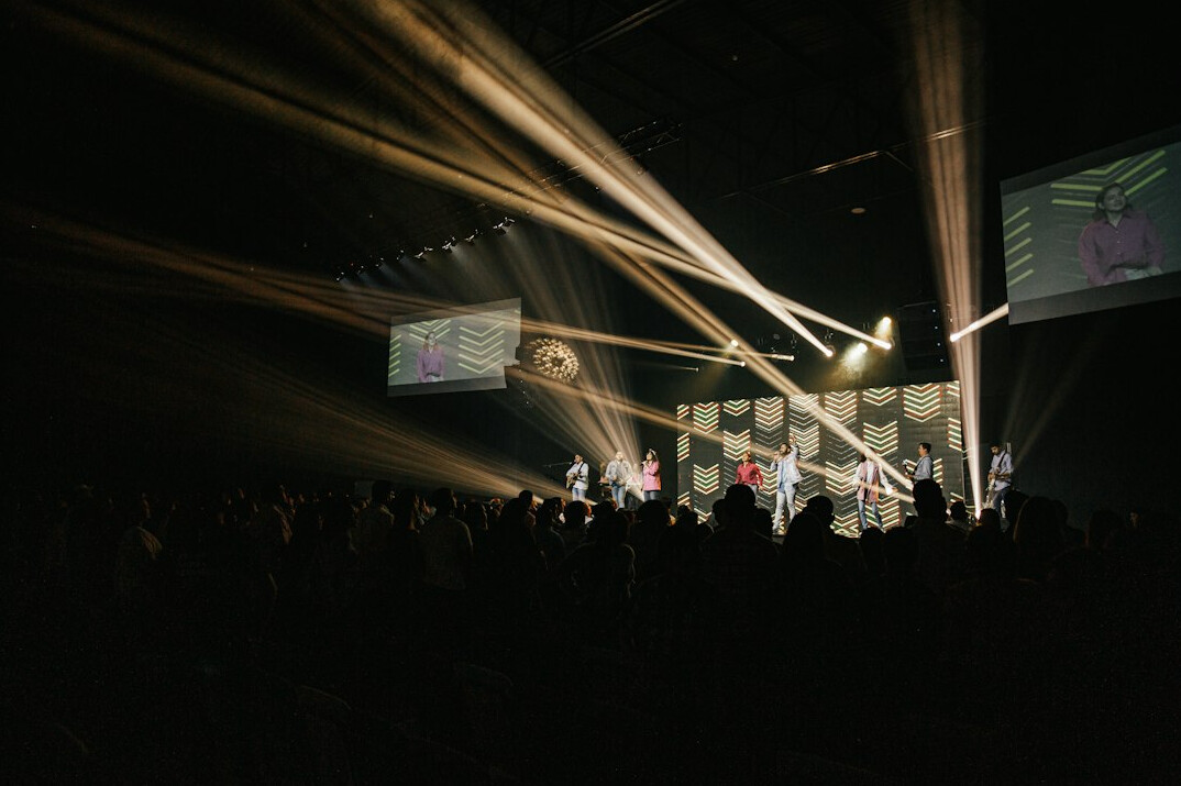 Live event stage with large screens and camera crew
